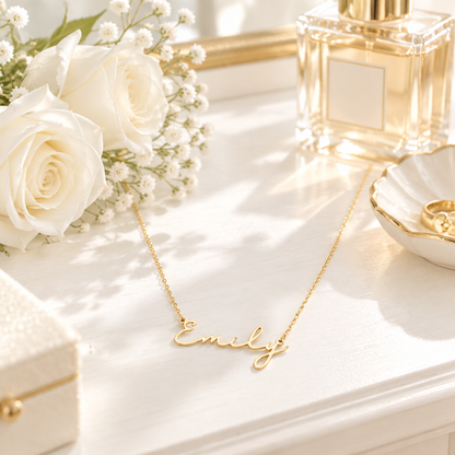 Collier prénom cursive or en scène lifestyle lumineuse – coiffeuse blanche, roses blanches, style chic Kylara