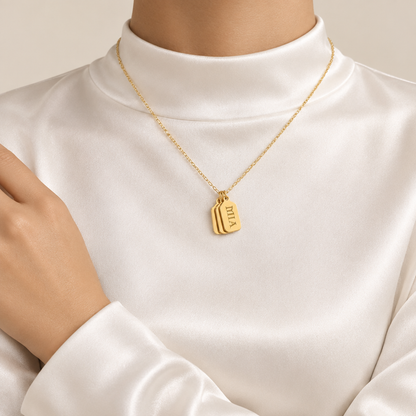 Mockup collier tag prénom gravé or, femme satin blanc jusqu'au cou, visage hors cadre, Kylara